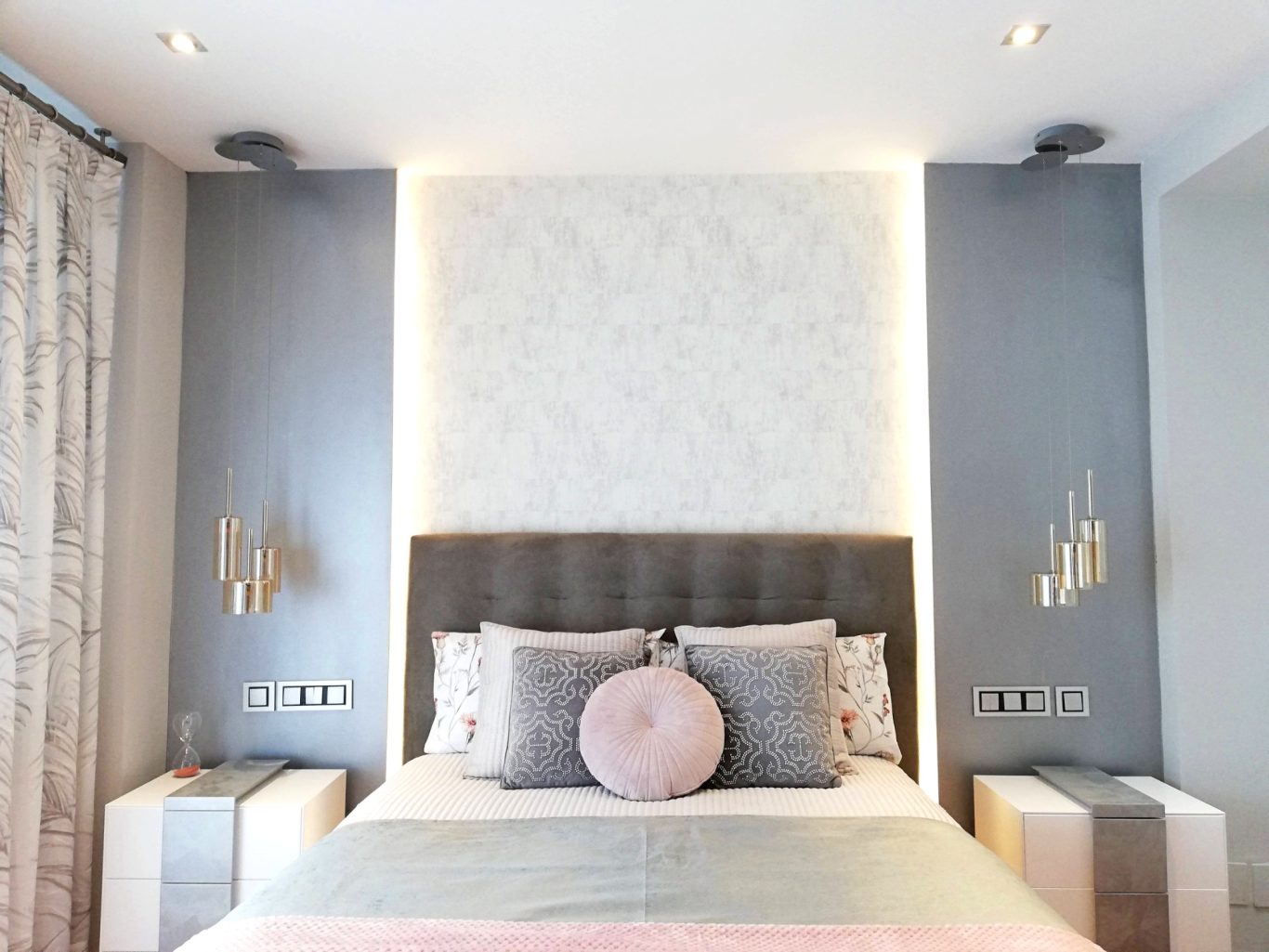 Habitación moderna con cama tapizada, cojines elegantes y paredes en tonos neutros.