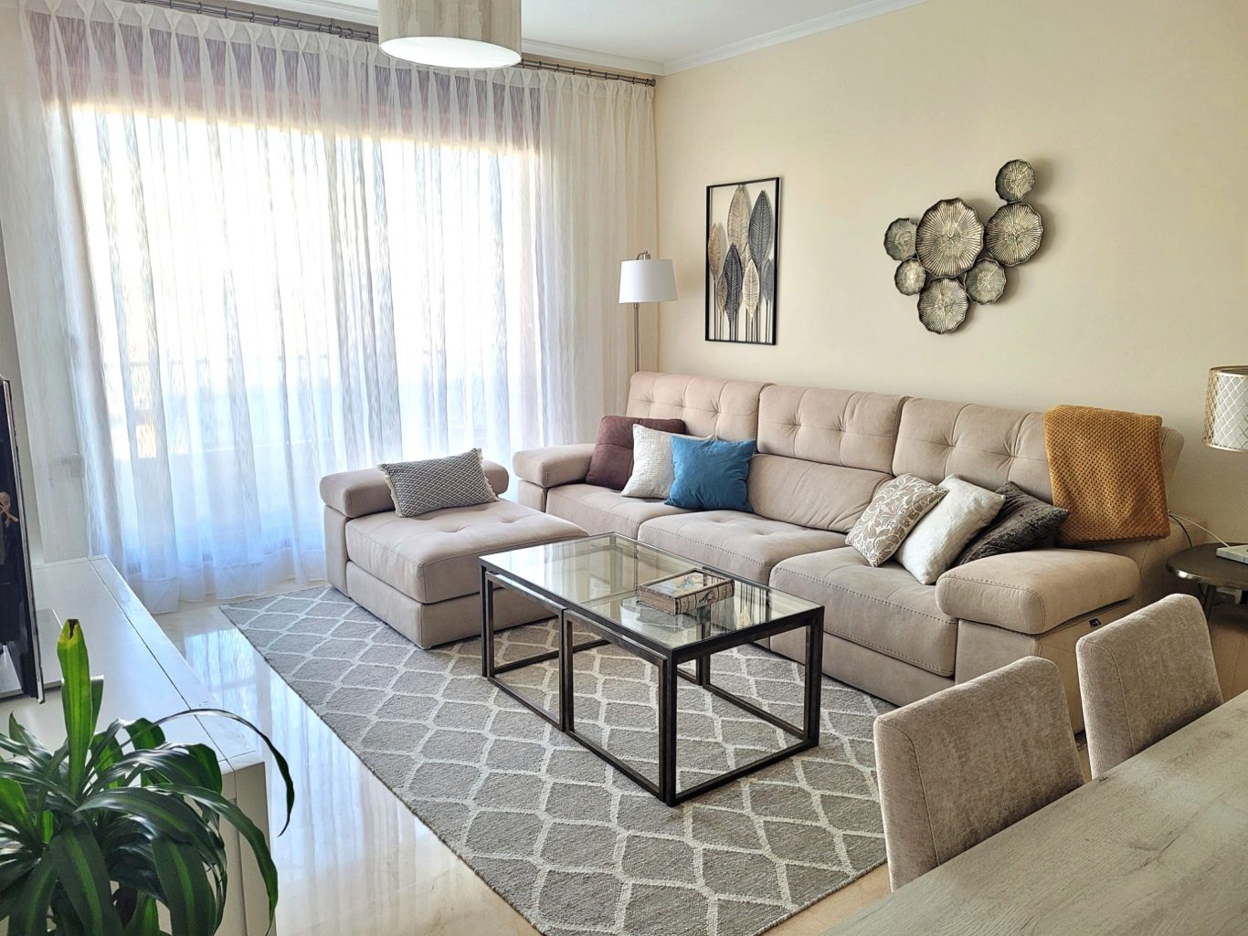 Sala de estar luminosa con sofá, mesa de vidrio y decoración moderna.